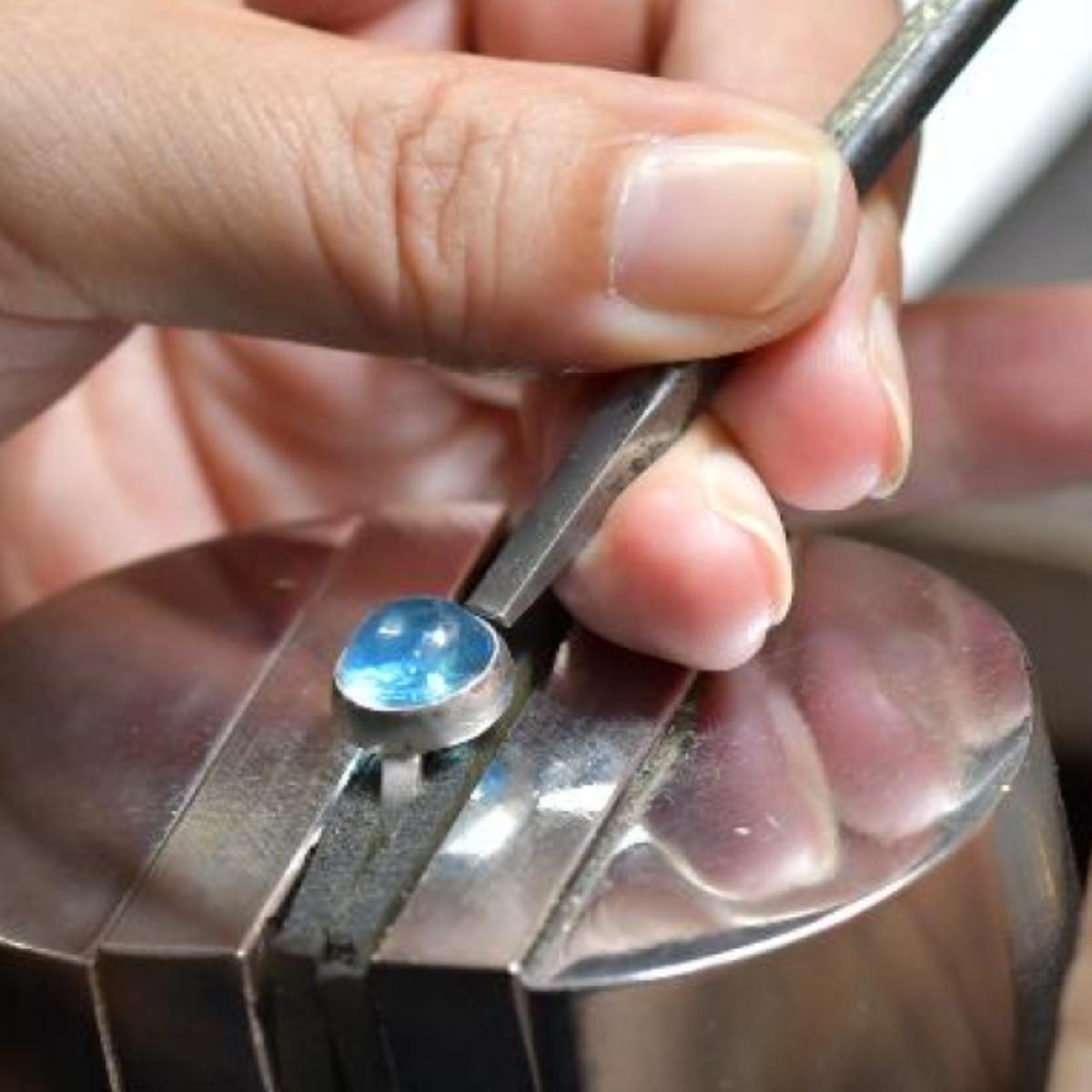 青い石を使ったジュエリーの石留め作業